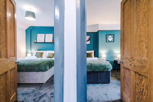 Duas camas num quarto com paredes azuis em Spacious 3br close to centre with parking em Knowsthorpe