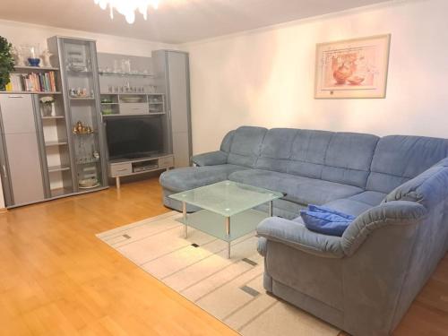 Schöne 2 Zimmer Wohnung في فورث: غرفة معيشة مع أريكة زرقاء وطاولة