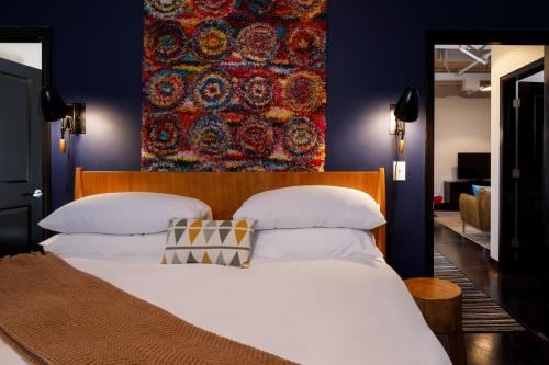 a bedroom with a large white bed with a tapestry on the wall at Hotel Clemons in Chattanooga