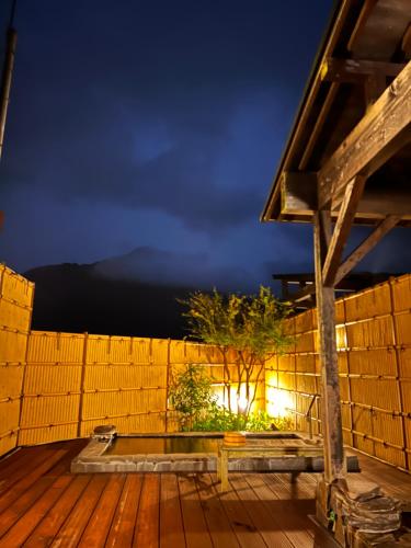a wooden deck with a wooden fence at night at 湯布院 旅館 やまなみ Ryokan YAMANAMI in Yufuin