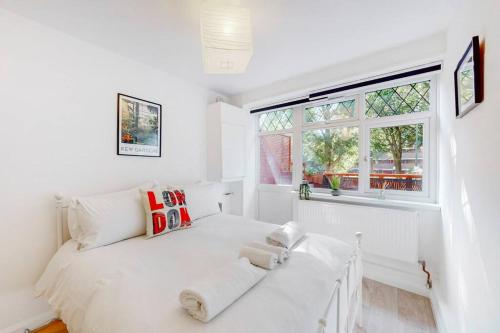 a white bedroom with a white bed and a window at Modern 4BD house with a private patio in Islington in London