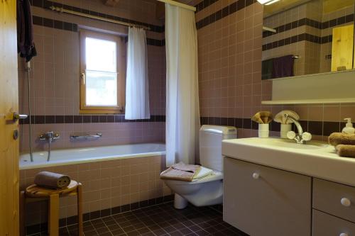 a bathroom with a toilet and a tub and a sink at Chasa Prümaran in Scuol