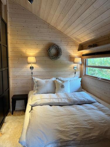 a bed in a room with a wooden wall at Special cottage in Sirdal in Tjørhom