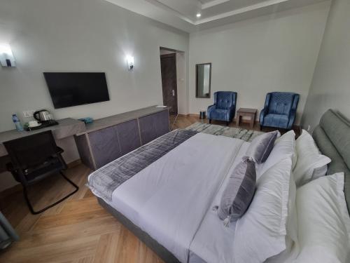 a bedroom with a large bed and a desk and two chairs at Solace Suites and Homes Maiduguri in Maiduguri