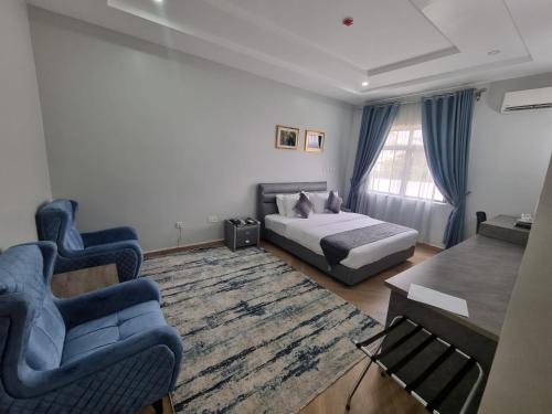 1 dormitorio con 1 cama, 2 sillas y mesa en Solace Suites and Homes Maiduguri, en Maiduguri