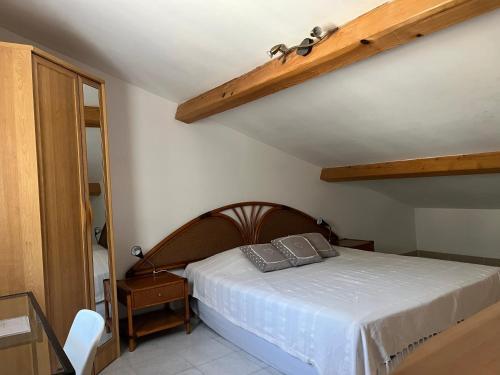 Schlafzimmer mit einem Bett mit einem Kopfteil aus Holz in der Unterkunft Les Restanques du Sud in Le Lavandou