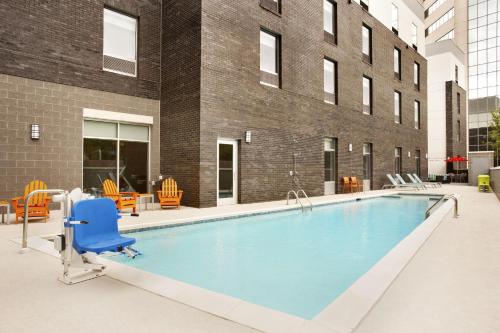 Home2 Suites by Hilton Greenville Downtown في غرينفيل: مسبح كبير بكرسي ازرق وكراسي