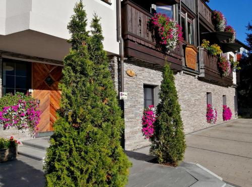 a group of trees in front of a building with flowers at Haus Ditzer - Villa Theresia in Zell am See