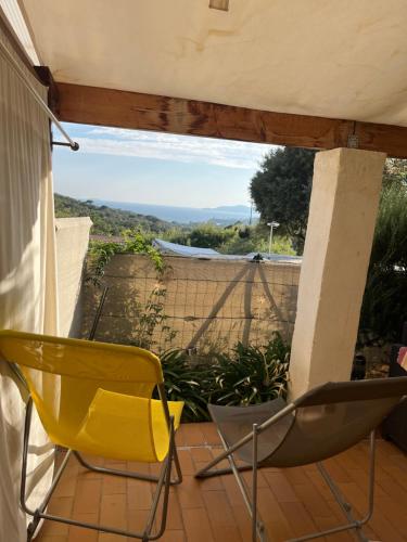 a yellow chair sitting on a porch with a view at Les Restanques du Sud in Le Lavandou