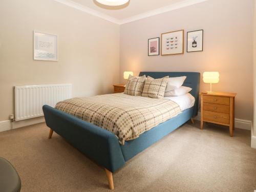 um quarto com uma cama azul e uma mesa de cabeceira em Y Castell Apartment 2 em Porthmadog