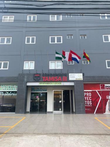 un edificio con banderas a un lado. en habitación con baño privado se comparte cocina cerca al aeropuerto, en Santa Cruz de la Sierra