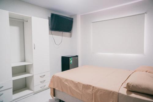 1 dormitorio con 1 cama y TV en la pared en habitación con baño privado se comparte cocina cerca al aeropuerto, en Santa Cruz de la Sierra