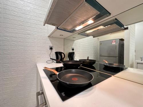 una cocina con 3 sartenes en una estufa en Sky Suites KLCC by KD Sky Home, en Kuala Lumpur