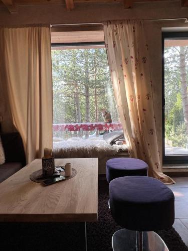 - un salon avec une table, deux tabourets et une fenêtre dans l'établissement Snježna vikendica, à Risovac