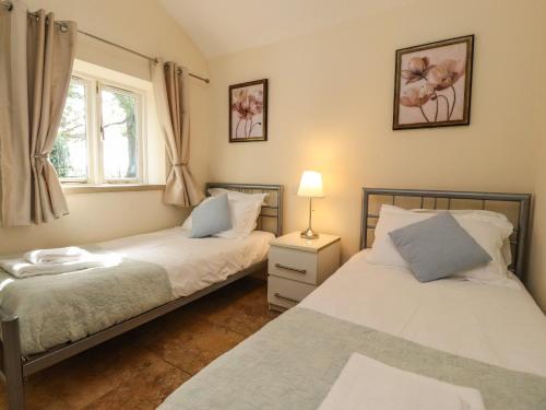 a bedroom with two beds and a window at Stable Cottage in Burton in Lonsdale