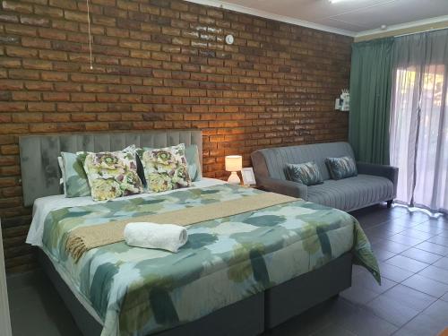 a bedroom with a bed and a chair and a brick wall at Garden cottages near Savannah Mall in Polokwane