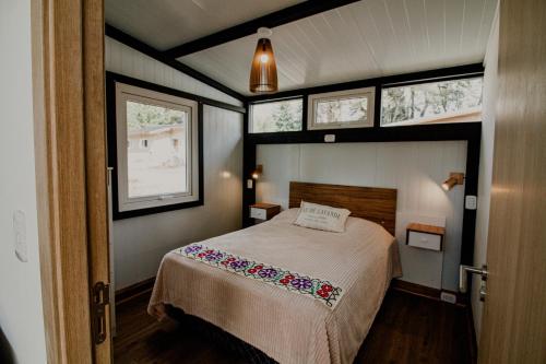 niewielka sypialnia z łóżkiem i 2 oknami w obiekcie Casa Amancay w mieście Bariloche