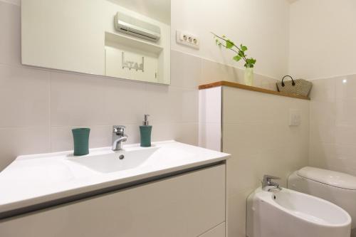 La salle de bains blanche est pourvue d'un lavabo et de toilettes. dans l'établissement Villa Capra Verde, à Ičići