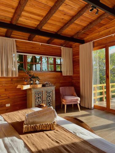 a bedroom with a bed and a chair and windows at La Perla Finca Hotel in Gigante