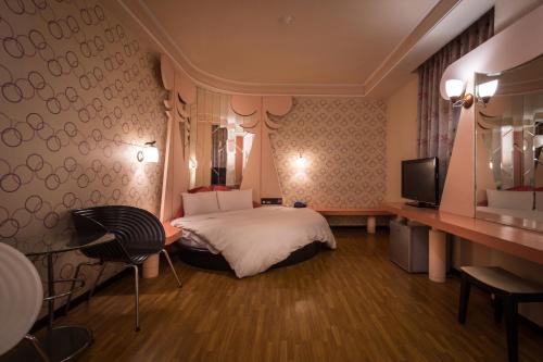 a hotel room with a bed and a television at Golden Phoenix Hotel in Kaohsiung