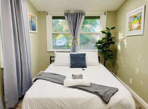 a bedroom with a large white bed with two windows at Artists Bungalow ARCADE King Beds near the beat in Sacramento