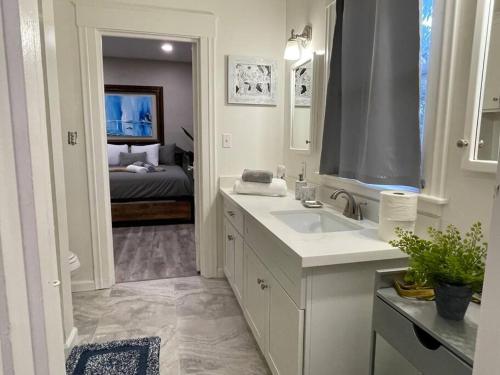 a white bathroom with a sink and a bedroom at Artists Bungalow ARCADE King Beds near the beat in Sacramento