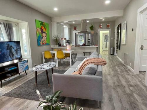 a living room with a gray couch and a kitchen at Artists Bungalow ARCADE King Beds near the beat in Sacramento