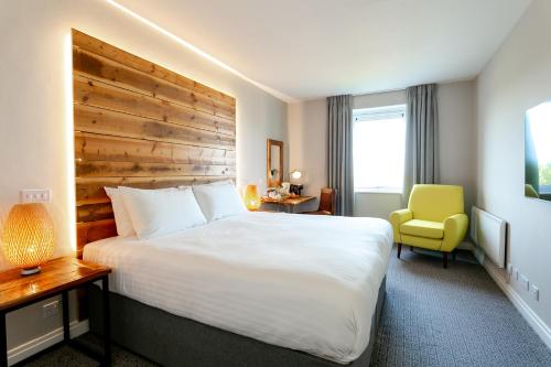 a hotel room with a large bed and a yellow chair at Cedar Court Bradford Hotel in Bradford