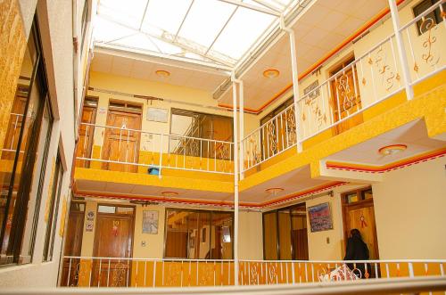 un grand bâtiment avec balcon et une femme marchant dans un couloir dans l'établissement HOSTAL SALARCITO, à Uyuni