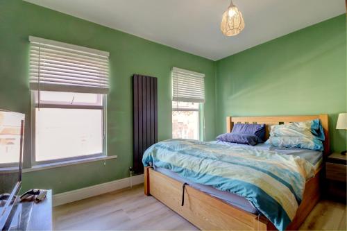 a green bedroom with a bed and two windows at Davis Street in London