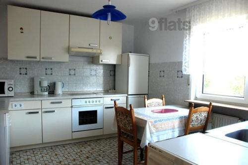 uma cozinha com electrodomésticos brancos e uma mesa com cadeiras em Fewowellnesspalast em Bad Nauheim