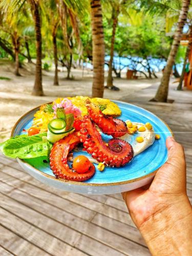 a person holding a blue plate of food with tentacles gmaxwell gmaxwell gmaxwellzos at Hotel Rosario de Mar by Tequendama in Isla Grande