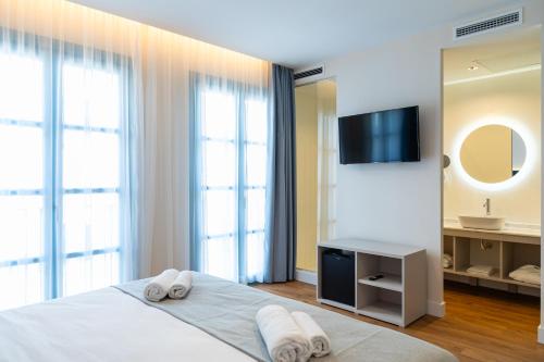 a bedroom with a bed and a tv and a mirror at Hotel Boutique La Brisa del Mar in Estepona