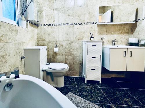 a bathroom with a tub and a toilet and a sink at Zoya’s Place in Harrow in Pinner