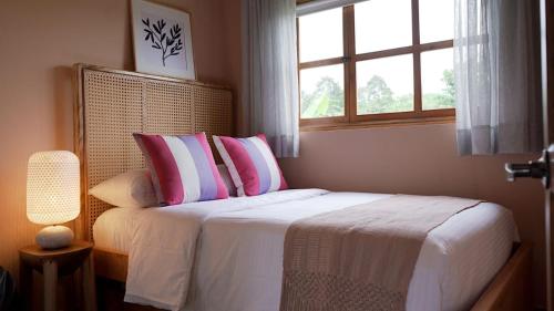a bedroom with a bed with pink and white pillows at LA PERLA FINCA HOTEL-Cabaña Amatista in Gigante