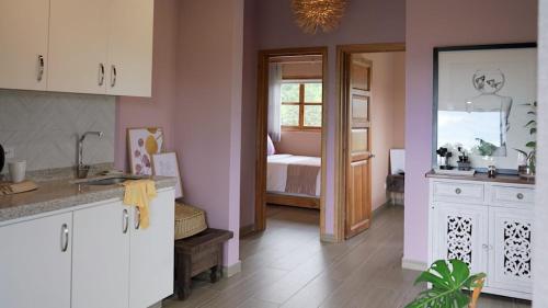 a kitchen with pink walls and white cabinets and a bedroom at LA PERLA FINCA HOTEL-Cabaña Amatista in Gigante