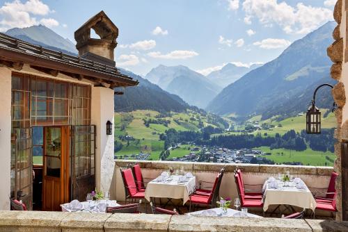 a balcony with tables and chairs with a view of mountains at Hotel Schloss Mittersill in Mittersill