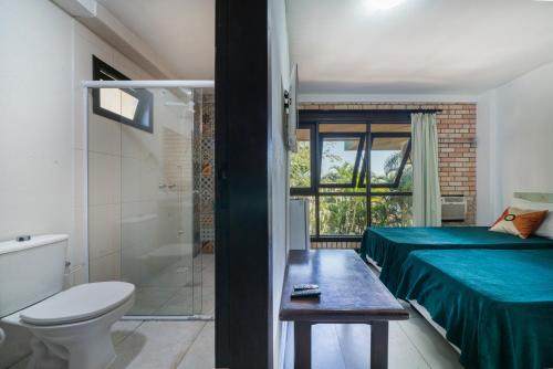 a bathroom with a bed and a toilet and a shower at Pousada Albacora in Bombinhas