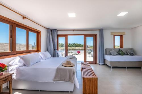 - une chambre avec un lit, un canapé et des fenêtres dans l'établissement Bahia Soul - Lake House - Barra Grande - Península de Maraú, à Barra Grande