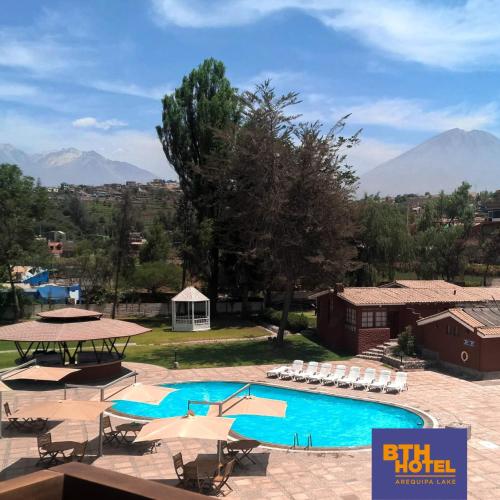 a large swimming pool with umbrellas and a resort at BTH Hotel Arequipa Lake in Arequipa