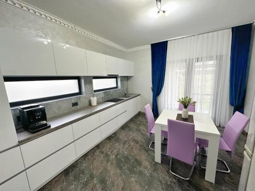 kuchnia z fioletowymi krzesłami i białym stołem w obiekcie Casa Anastasia w mieście Oradea