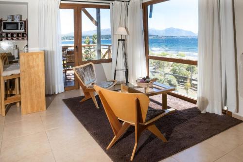 a living room with a table and a view of the ocean at Blue Aparts Dina Huapi Bariloche in Dina Huapi