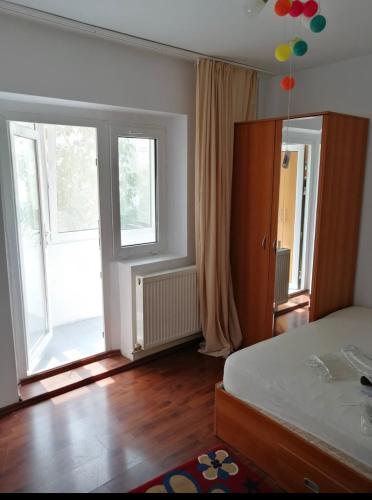 - une chambre avec un lit et 2 grandes fenêtres dans l'établissement Apartament Ploiesti, à Ploieşti