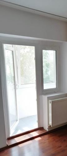 une chambre vide avec 2 fenêtres et du parquet dans l'établissement Apartament Ploiesti, à Ploieşti