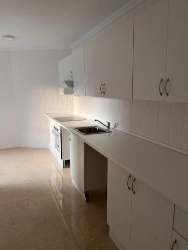 una cocina con armarios blancos y fregadero en Mars Suites Alondra en Madrid