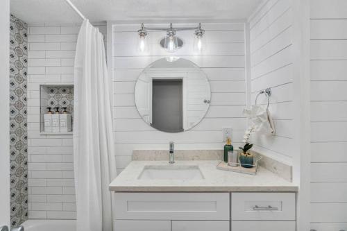 a white bathroom with a sink and a mirror at Clearwater 2 story pool home mins from the beach in Clearwater