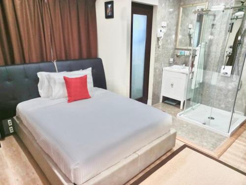 a bedroom with a bed with a red pillow and a shower at Myah's Hotel in Brighton Village