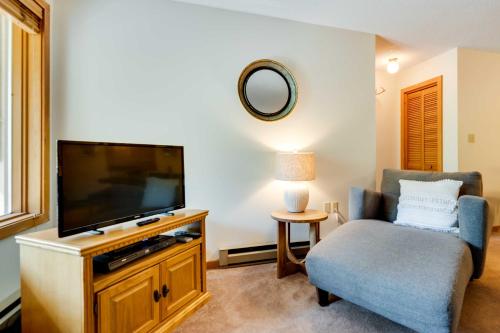 a living room with a flat screen tv and a chair at Riverfront Lincoln Condo with Patio and Pool Access! in Lincoln