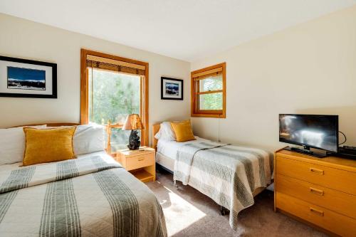 a bedroom with two beds and a television in it at Riverfront Lincoln Condo with Pool Mins to Loon Mtn in Lincoln