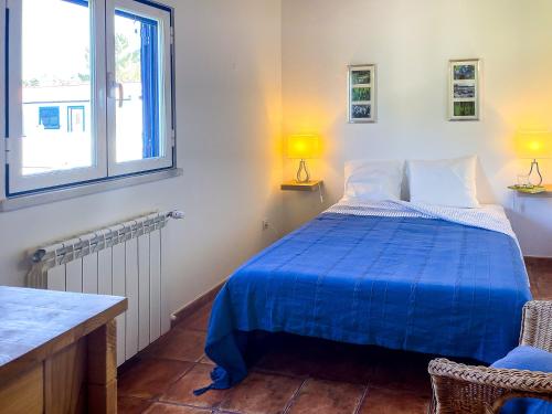 um quarto com uma cama azul e 2 janelas em Quinta do Cutato - Soba Guest House em Santo Estêvão